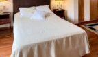 Dormitorio luminoso con cama doble, suelo de parqué y armario de madera en la elegante casa adosada de Palma de Mallorca.