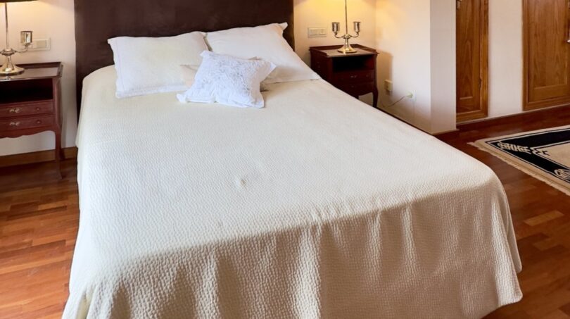 Dormitorio luminoso con cama doble, suelo de parqué y armario de madera en la elegante casa adosada de Palma de Mallorca.