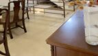 Sala de estar luminosa con elegante escalera de caracol, suelos de mármol y muebles clásicos de madera en la casa adosada de Palma