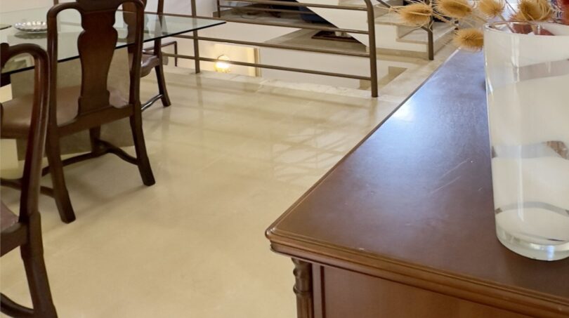 Sala de estar luminosa con elegante escalera de caracol, suelos de mármol y muebles clásicos de madera en la casa adosada de Palma