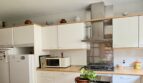 Cocina luminosa con armarios blancos, estufa de gas, campana extractora y refrigerador en la casa adosada Palma de Mallorca.