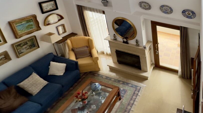 Sala de estar luminosa con techo alto, sofás azules, chimenea y tragaluces en la casa adosada Palma de Mallorca