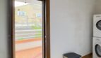 Lavandería con lavadora Bosch apilada, acceso a terraza y vista a las instalaciones deportivas en Palma de Mallorca.