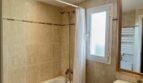 Bright bathroom with bathtub, shower, window and towel heating element in Mallorca apartment