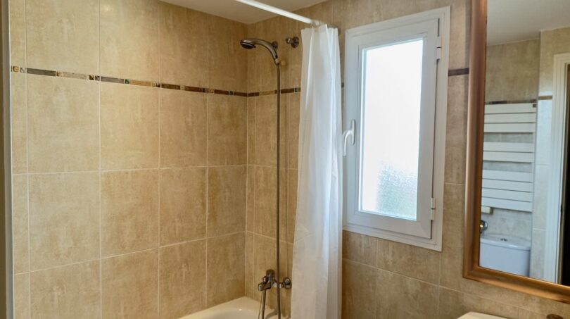 Bright bathroom with bathtub, shower, window and towel heating element in Mallorca apartment