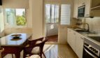 Bright kitchen with dining area, white built-in cabinets and access to the terrace with nature view in Mallorca.