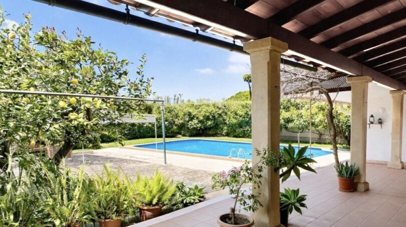 Überdachte Terrasse mit Säulen, Topfpflanzen und Blick auf den großen Pool des Chalets in Palmanyola.