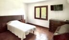 Schlafzimmer des Chalets in Palmanyola mit Einzelbett, Holzmöbeln, Terrakottaboden und Fenster zum Garten.