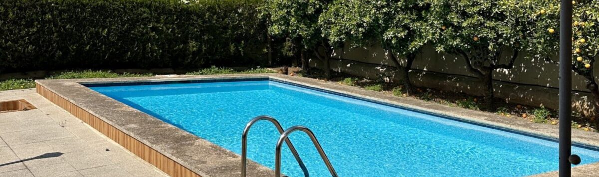 Privater Pool des Einfamilienchalets in Palmanyola, umgeben von Zitrusbäumen und Hecken, mit Bergblick.
