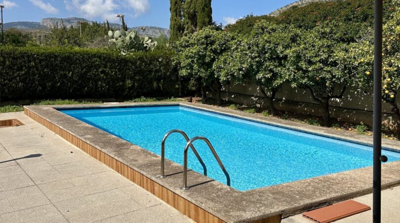 Privater Pool des Einfamilienchalets in Palmanyola, umgeben von Zitrusbäumen und Hecken, mit Bergblick.