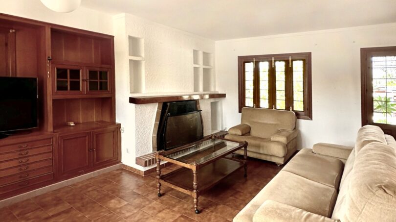 Wohnzimmer des Chalets in Palmanyola mit Kamin, Holzmöbeln, Sofa und Terrakottaboden