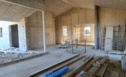 Rohbau-Innenbereich der Finca in Vilafranca de Bonany mit Holzdecke, Betonwänden und Baumaterialien.