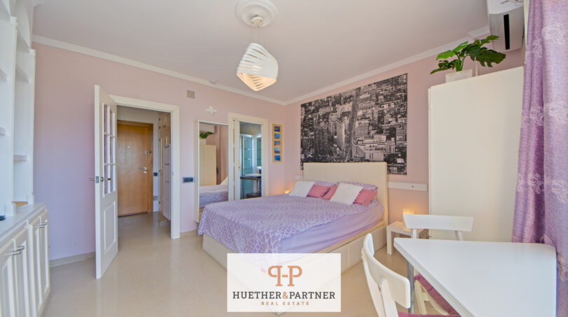 Helles Studio-Schlafzimmer in Cales de Mallorca mit Doppelbett, rosa Wänden und modernem Stadtbild-Wandbild.