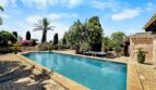 Piscina exterior de la Finca en Felanitx con jardín mediterráneo, palmeras y buganvilia bajo cielo azul