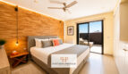 Modernes Schlafzimmer der Luxusvilla in Cala Murada mit Holzwandverkleidung, Deckenventilator und Balkonzugang.