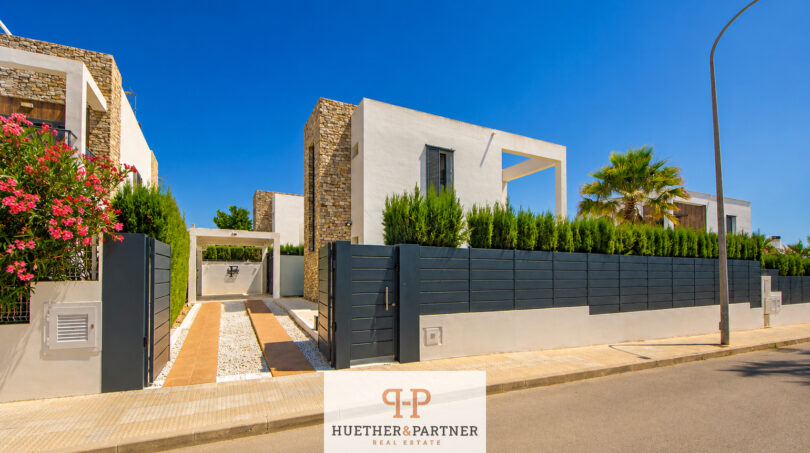Moderne Bauhausvilla in Cala Murada mit Natursteinakzenten, Einfahrtstor und gepflegtem Gartenbereich.