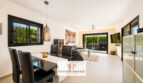 Modernes Wohn-Esszimmer der Bauhausvilla in Cala Murada mit schwarzen Akzenten, Kamin und Gartenblick