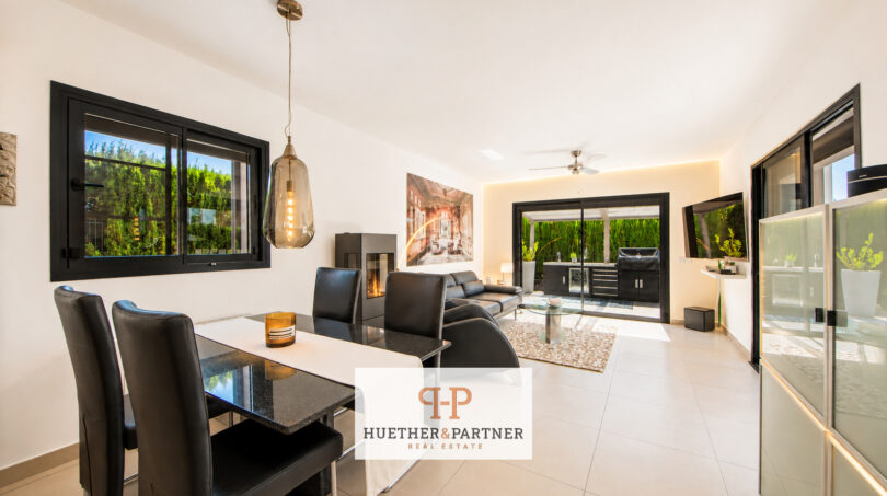 Modernes Wohn-Esszimmer der Bauhausvilla in Cala Murada mit schwarzen Akzenten, Kamin und Gartenblick