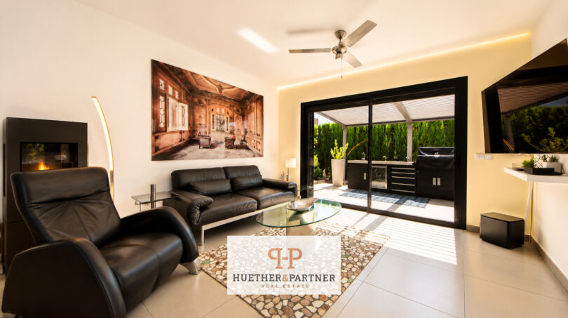 Modernes Wohnzimmer der Luxusvilla in Cala Murada mit Ledersofa, Kamin und Zugang zur Außenküche