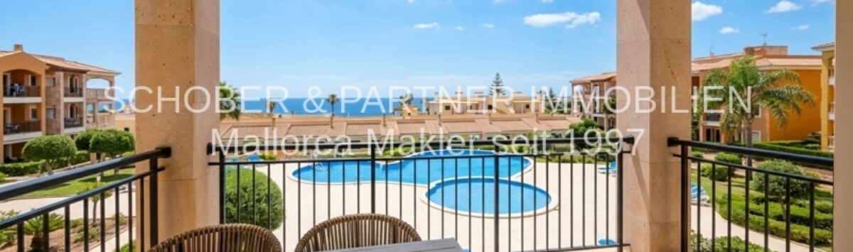 Sonnige Terrasse mit Gartenmöbeln und Blick auf den Gemeinschaftspool der Anlage in Cala Magrana