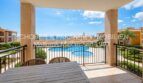 Sonnige Terrasse mit Gartenmöbeln und Blick auf den Gemeinschaftspool der Anlage in Cala Magrana