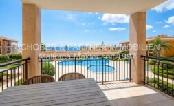 Sonnige Terrasse mit Gartenmöbeln und Blick auf den Gemeinschaftspool der Anlage in Cala Magrana