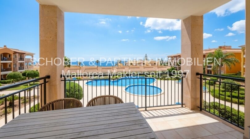 Sonnige Terrasse mit Gartenmöbeln und Blick auf den Gemeinschaftspool der Anlage in Cala Magrana