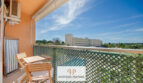 Sonniger Balkon mit Holzmöbeln, Gitterzaun und Blick auf Pool und Hotelgebäude in Cales de Mallorca
