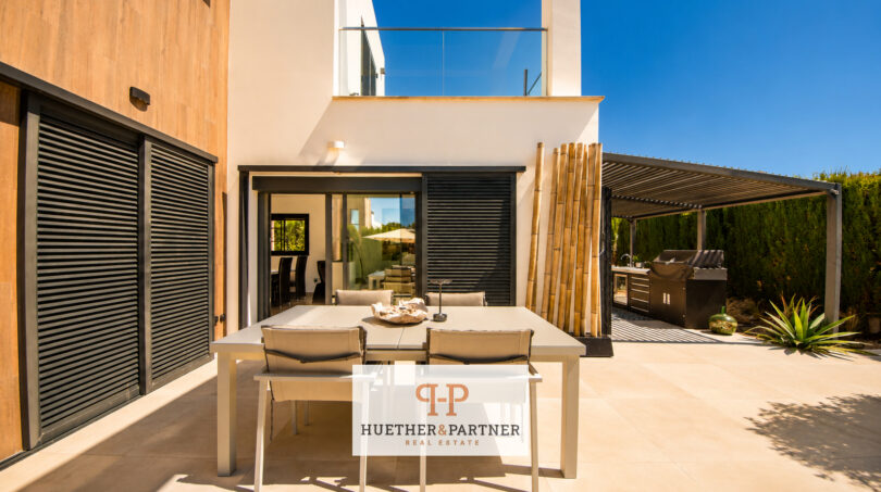 Moderne Außenterrasse der Luxusvilla in Cala Murada mit Esstisch, Pergola, Außenküche und elegantem Loungebereich.