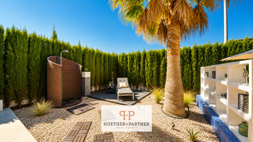 Privater Garten der Luxusvilla in Cala Murada mit Palme, Outdoor-Dusche, Liege und Naturstein-Bepflanzung.