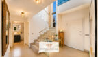 Heller Eingangsbereich der Luxusvilla in Cala Murada mit moderner Treppe, Glasgeländer und elegantem Fliesenboden.