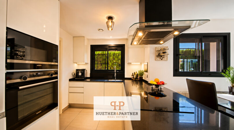 Moderne Luxusküche mit schwarzen Granitarbeitsflächen, Siemens-Einbaugeräten und Kochinsel in Bauhausvilla Cala Murada
