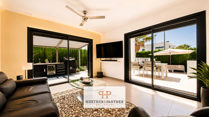 Helles Wohnzimmer der Luxusvilla in Cala Murada mit Ledersofas, Deckenventilator und großen Schiebetüren zur Terrasse.