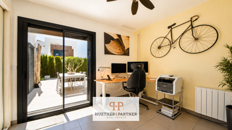 Modernes Heimarbeitszimmer der Bauhausvilla in Cala Murada mit Glasschiebetür zur sonnigen Terrasse und Fahrrad-Wanddeko.