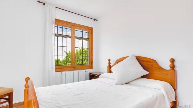 Helles Schlafzimmer mit Holzfenstern und effizienter Raumnutzung