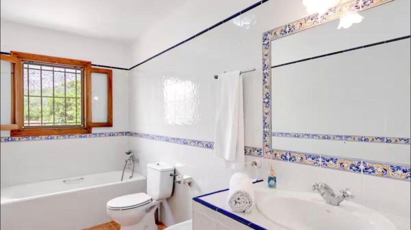 Helles Badezimmer mit Wanne, Dusche und großformatigen Holzfenstern