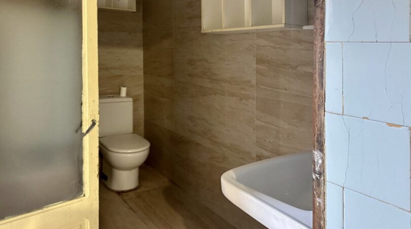 Badezimmer mit WC und Badewanne, beige Fliesenwände, renovierungsbedürftig, Stadthaus Manacor