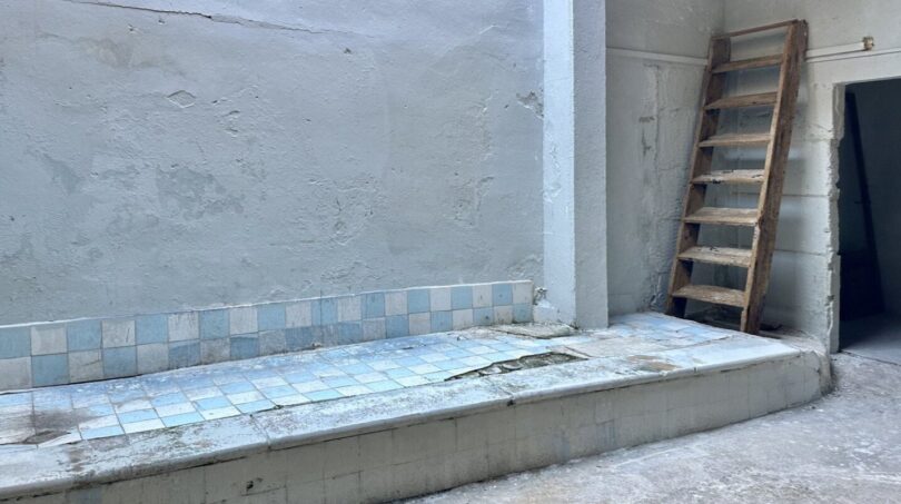Renovierungsbedürftiger Patio mit blauen Bodenfliesen, verwitterten Wänden und Holzleiter in Stadthaus, Manacor.