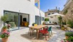Sonnige Terrasse mit bunten Stühlen, Esstisch und Lounge-Bereich am Stadthaus in Artà, Mallorca.