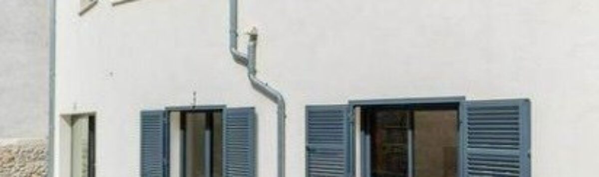 Außenansicht Stadthaus Artà: helle Fassade, blaue Fensterläden, Terrasse, moderner Baustil auf Mallorca