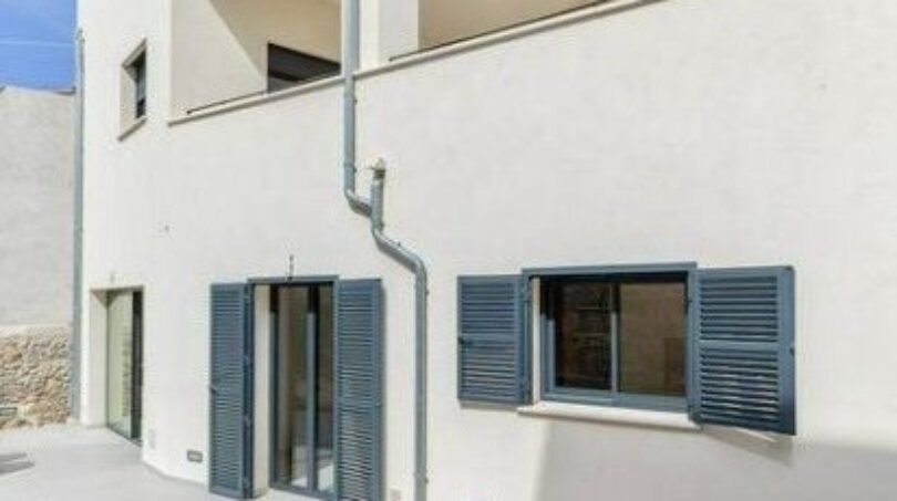 Außenansicht Stadthaus Artà: helle Fassade, blaue Fensterläden, Terrasse, moderner Baustil auf Mallorca