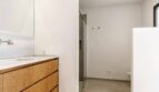 Modernes Badezimmer mit Holzwaschtisch, Spiegel und Glasdusche im Stadthaus Artà, Mallorca.