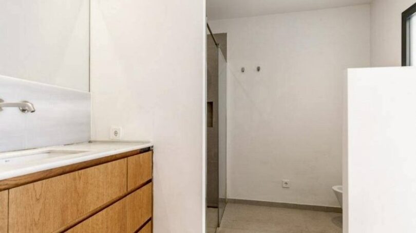 Modernes Badezimmer mit Holzwaschtisch, Spiegel und Glasdusche im Stadthaus Artà, Mallorca.