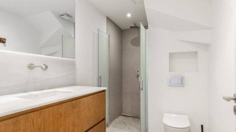 Modernes Badezimmer mit Holzwaschtisch, Glasdusche und Wand-WC im Stadthaus Artà