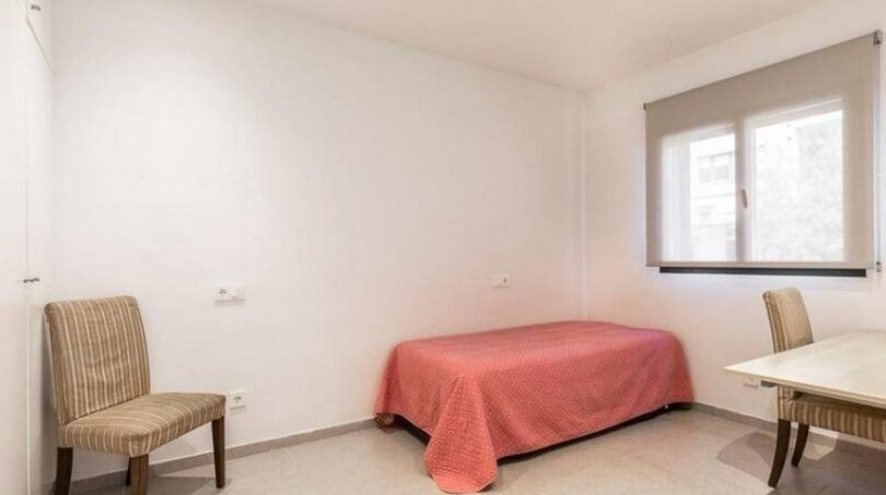 Helles Schlafzimmer mit Einzelbett, zwei Stühlen und Schreibtisch im Stadthaus Artà, Mallorca.