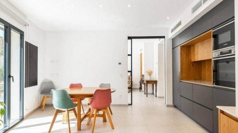 Helles Esszimmer mit bunten Stühlen und moderner grauer Einbauküche in stilvollem Stadthaus in Artà