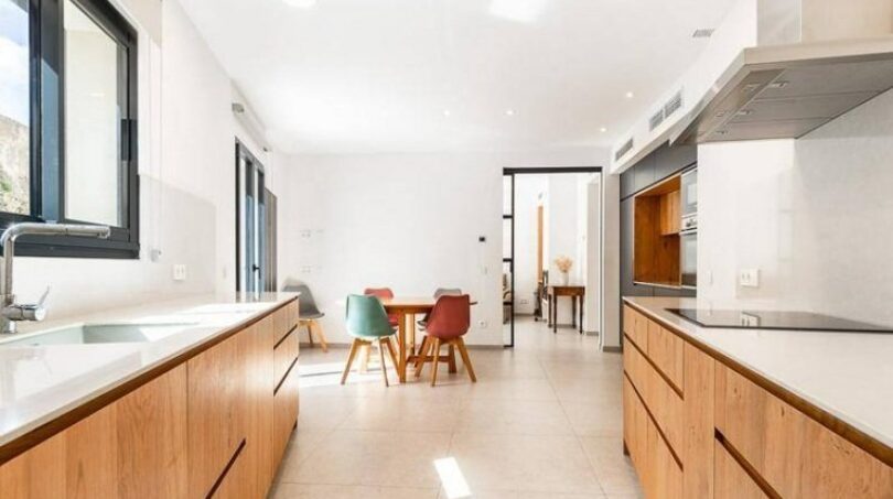 Moderne Küche mit Holzfronten und weißer Arbeitsplatte, Essbereich mit bunten Stühlen, Stadthaus Artà Mallorca