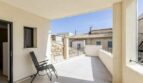 Überdachte Terrasse mit Sessel, Fliesenbelag und Blick auf mediterrane Nachbarhäuser in Artà, Mallorca