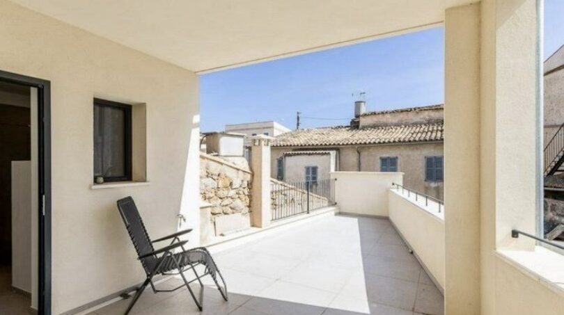 Überdachte Terrasse mit Sessel, Fliesenbelag und Blick auf mediterrane Nachbarhäuser in Artà, Mallorca