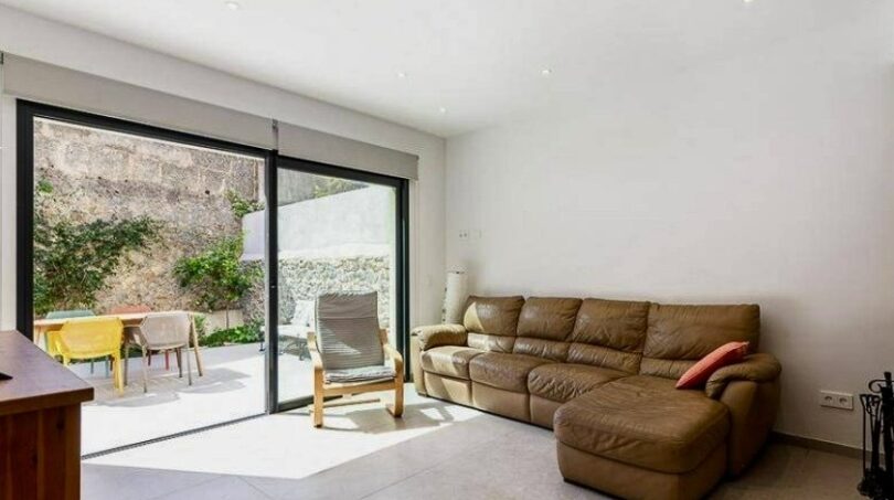 Helles Wohnzimmer mit Ledersofa, Glasschiebetür und sonniger Terrasse im Stadthaus in Artà